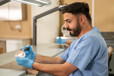 معالجة النخر والتسوس، المعدات والادوات اللازمة لإجراء الفحوصات، صورة مقربة من الجانب لطالبان عربيان خليجيان سعوديان بكلية الأسنان يرتديان القفازات يقومان بفحص طاقم أسنان، مفهوم التدريب العملي، الأساليب العلاجية المتبعة للعناية بالفم