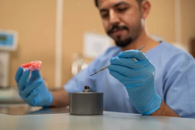 The therapeutic methods used for oral care, treatment of cavities and placement of fillings, higher education in the Kingdom of Saudi Arabia, the equipment and tools necessary for conducting examinations, a close-up image of a Saudi Arab university student in the College of Dentistry wearing gloves and sculpting a dental prosthesis.