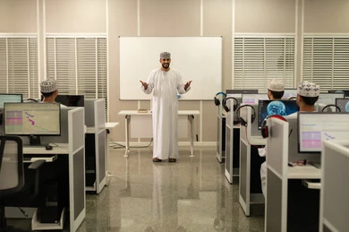تطوير أساليب التعليم الجامعي في سلطنه عمان، تركيز وانسجام الطلاب أثناء الاستماع إلى المحاضرة، معلم عربي خليجي عماني يرتدي الدشداشة و الكمة يقوم بشرح المحاضرة للطلاب، ورش عمل ودورات تدريبية، التعليم الجامعي العماني