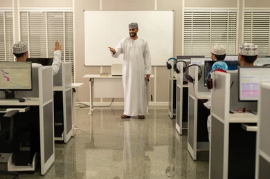 Raising hands to ask questions in the classroom, listening to the lecture, an Arab Gulf Omani university professor wearing a dishdasha and a kumma explaining to his students in the lecture, academic universities in the Sultanate of Oman, developed colleges and universities.