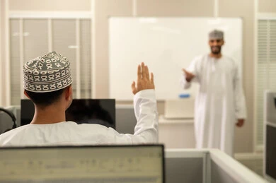 الإستماع الى المحاضره، رفع اليدين داخل الفصل، أستاذ جامعي عربي خليجي عماني يرتدي الدشداشة و الكمة يشرح لطلابه في المحاضره, جامعات أكاديميه في سلطنه عمان , كليات وجامعات متطوره