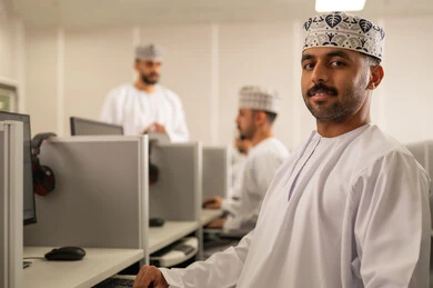 ورش عمل ودورات تدريبية، تطوير أساليب التعليم الجامعي في سلطنه عمان، طالب عربي خليجي عماني يرتدي الدشداشة و الكمة يجلس امام الحاسوب يقوم بالمناقشة مع المعلم، التعليم الجامعي العماني