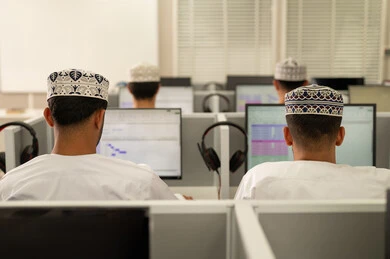 الدراسة الجامعية عبر الكمبيوتر، الانجاز و التفوق في المرحلة الجامعية، صورة من الخلف لمجموعه من الطلاب العربيون الخليجيون العمانيون يرتدون الدشداشة و الكمة يجلسون امام الحاسوب، جامعات أكاديميه في سلطنه عمان