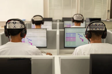 الدراسة الالكترونية في الجامعة، الانجاز و التفوق في المرحلة الجامعية، صورة من الخلف لمجموعه من الطلاب العربيون الخليجيون العمانيون يرتدون الدشداشة و الكمة يقومون بالنظر الى الحاسوب بايماءات الاندماج و التركيز، استخدام تقنية الهيدفون فى التعليم