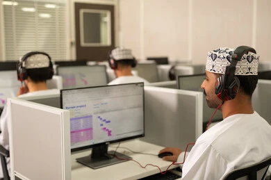 المحاضرات الدراسية عبر الكمبيوتر، الانجاز و التفوق في المرحلة الجامعية، صورة من الخلف لمجموعه من الطلاب العربيون الخليجيون العمانيون يرتدون الدشداشة و الكمة يقومون بالنظر الى الحاسوب بايماءات الاندماج و التركيز، استخدام تقنية الهيدفون فى التعليم