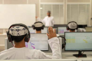 استخدام تقنية الهيدفون، أستاذ جامعي عربي خليجي عماني يرتدي الدشداشة و الكمة يشرح لطلابه في المحاضره, رفع اليدين للتفاعل والمشاركه, الإستماع الى المحاضره, جامعات أكاديميه في سلطنه عمان , كليات وجامعات متطوره