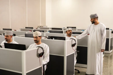 كليات وجامعات متطوره، التفوق بالاجتهاد والمثابرة، معلم عربي خليجي إماراتي يرتدي الدشداشة والغترة يقوم بشرح شي ما، جامعات أكاديميه في سلطنه عمان ، مجموعه من الطلاب عمانوين يجلسون امام الحاسوب يقومون بالإستماع الى المحاضره