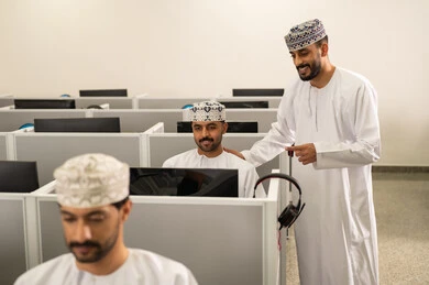 مفهوم الاجتهاد وطلب التفوق، معلم عربي خليجي إماراتي يرتدي الدشداشة والغترة يقوم بشرح شي ما، جامعات أكاديميه في سلطنه عمان ، مجموعه من الطلاب عمانوين يجلسون امام الحاسوب يقومون بالإستماع الى المحاضره, كليات وجامعات متطوره