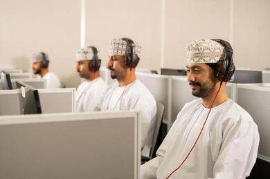 Gestures of integration and focus, achievement and excellence in the university stage, higher education in the Sultanate of Oman, a group of Arab Gulf students from Oman wearing the dishdasha and kumma, putting headphones on their heads, are listening to the lesson.