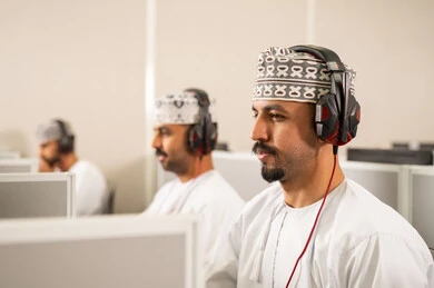 Higher education in the Sultanate of Oman, gestures of integration and focus, a group of Arab Gulf Omani students wearing the dishdasha and kumma are wearing headphones on their heads listening to the lesson, achievement and excellence in the university stage.
