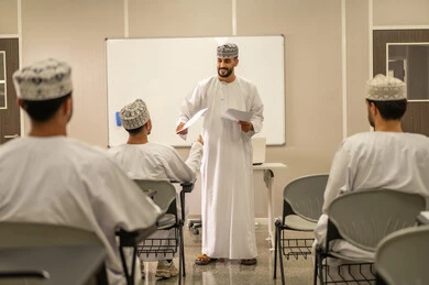 الدراسة و الاجتهاد من اجل التفوق, مجموعة من التلاميذ العمانيين يقومون بالاستعداد لحل أسئلة الامتحان, اهداف التربية و التعليم, التعليم في سلطنه عمان ,معلم عربي خليجي عماني يرتدي الدشداشة و الكمه يقوم بتوزيع ورق الامتحان على الطلاب