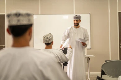 التركيز على التعليم والاجتهاد للتميز, مجموعة من التلاميذ العمانيين يقومون بالاستعداد لحل أسئلة الامتحان, اهداف التربية و التعليم, التعليم في سلطنه عمان , معلم عربي خليجي عماني يرتدي الدشداشة و الكمه يقوم بتوزيع ورق الامتحان على الطلاب
