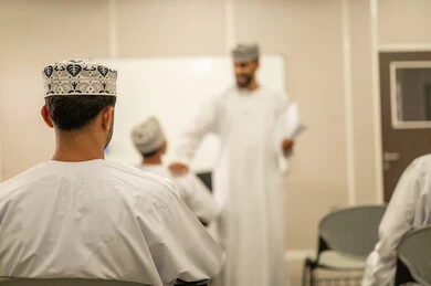 Hard work and studying for excellence, a group of Omani students preparing to solve exam questions, the goals of education and teaching, education in the Sultanate of Oman, an Arab Gulf Omani teacher wearing a dishdasha and kumma distributing exam papers to the students.