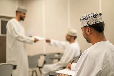 السعي والاجتهاد للحصول على التفوق, مجموعة من التلاميذ العمانيين يقومون بالاستعداد لحل أسئلة الامتحان, اهداف التربية و التعليم, التعليم في سلطنه عمان ,معلم عربي خليجي عماني يرتدي الدشداشة و الكمه يقوم بتوزيع ورق الامتحان على الطلاب