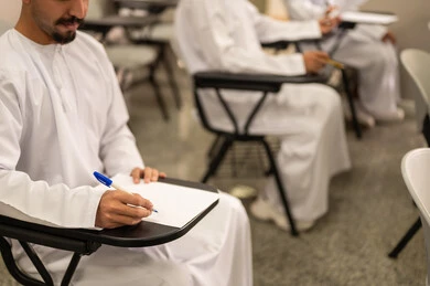 طلب العلا والمثابرة والحرص على النجاح، ايماءات تدل على التركيز والتفكير بالإجابة، طالب عربي خليجي عماني يرتدي الدشداشة و الكمة يقوم بحل اسئله الامتحان