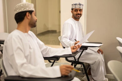 The pursuit of achieving success and academic excellence, a close-up image of two Arab Gulf Omani students solving exam questions, the goals of education and teaching, education in the Sultanate of Oman, expressions of happiness and joy.