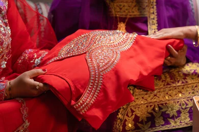 فستان باللون الأحمر من الازياء التقليدية، احتفالات سعيدة ومناسبات وأفراح، الاهتمام والعناية بالأناقة والجمال، منتجات ومساحيق التجميل، سيداتان عربيتان خليجيتان اماراتيتان يقوموا بعرض الفساتين والمجوهرات، إيماءات السعادة والفرح ، الاحتفال بليلة العمر