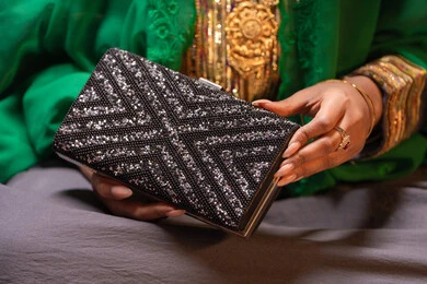 حقيبة صغيرة بتصميم أنيق، منتجات ومساحيق التجميل، التقاليد في التقدم لطلب يد الفتاة، احتفالات سعيدة ومناسبات، صورة مقربة لسيدة عربية خليجية اماراتية تقوم باستعراض التحضيرات والتجهيزات للزفاف ترتدي الملابس التقليدية، إيماءات السعادة والفرح، الاحتفال بليلة العمر