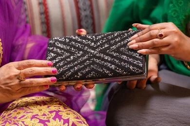 سيدة تهدي حقيبة صغيرة بتصميم أنيق، منتجات ومساحيق التجميل، التقاليد في التقدم لطلب يد الفتاة، احتفالات سعيدة ومناسبات، صورة مقربة لسيدة عربية خليجية اماراتية تقوم باستعراض التحضيرات والتجهيزات للزفاف ترتدي الملابس التقليدية، إيماءات السعادة والفرح، الاحتفال بليلة العمر