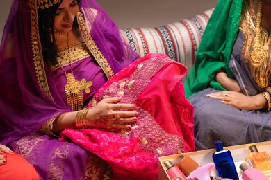 A display of a summer-colored dress suitable for weddings, beauty products and cosmetics, traditions in proposing to a girl, happy celebrations and occasions, a close-up image of two Emirati Gulf Arab women showcasing the preparations and arrangements for the wedding, gestures of happiness and joy, celebrating the night of a lifetime.