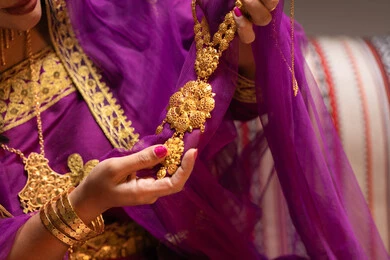 عرض قطعة من الحلي عقد ذهبي، منتجات ومساحيق التجميل، التقاليد في التقدم لطلب يد الفتاة، احتفالات سعيدة ومناسبات، صورة مقربة لسيدة عربية خليجية اماراتية تقوم باستعراض التحضيرات والتجهيزات للزفاف ترتدي الملابس التقليدية، إيماءات السعادة والفرح، الاحتفال بليلة العمر