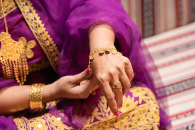 التفاخر بالحلي سوار ذهبي، منتجات ومساحيق التجميل، التقاليد في التقدم لطلب يد الفتاة، احتفالات سعيدة ومناسبات، صورة مقربة لسيدة عربية خليجية اماراتية تقوم باستعراض التحضيرات والتجهيزات للزفاف ترتدي الملابس التقليدية، إيماءات السعادة والفرح، الاحتفال بليلة العمر