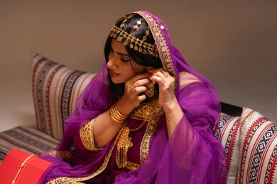 ارتداء صيغة حلق ذهبي فاخر، منتجات ومساحيق التجميل، التقاليد في التقدم لطلب يد الفتاة، احتفالات سعيدة ومناسبات، صورة مقربة لسيدة عربية خليجية اماراتية تقوم باستعراض التحضيرات والتجهيزات للزفاف ترتدي الملابس التقليدية، إيماءات السعادة والفرح، الاحتفال بليلة العمر