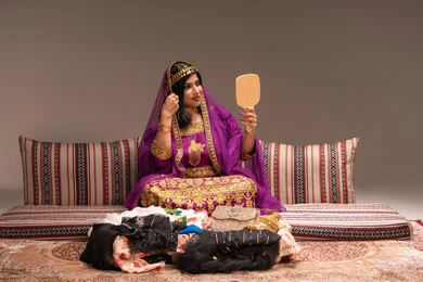 مفهوم التزيين والإطلالة المتألقة، الاحتفالات والمناسبات السعيدة ،التزين بالحلي و المجوهرات الذهبية ، استخدام مساحيق التجميل لإبراز الجمال، عروس عربية خليجية اماراتية ترتدي الزي التقليدي الشعبي تنظر لنفسها بالمرآة، الاستعداد للاحتفال بليلة العمر