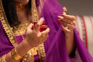 زجاجة عطر بالون الأحمر، مفهوم التزيين والإطلالة المتألقة، التزين بالحلي و المجوهرات الذهبية ، استخدام مساحيق التجميل لإبراز الجمال، عروس عربية خليجية اماراتية ترتدي الزي التقليدي الشعبي تقوم باستعراض التحضيرات والتجهيزات للزفاف، الاستعداد للاحتفال بليلة العمر