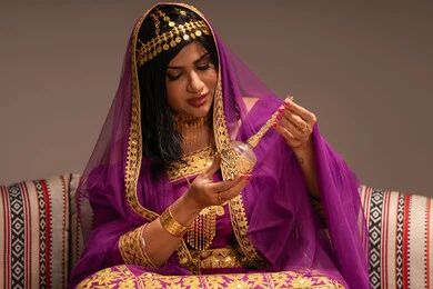 مرش الطيب في الزفاف، مفهوم التزيين والإطلالة المتألقة، التزين بالحلي و المجوهرات الذهبية ، استخدام مساحيق التجميل لإبراز الجمال، عروس عربية خليجية اماراتية ترتدي الزي التقليدي الشعبي تقوم باستعراض التحضيرات والتجهيزات للزفاف، الاستعداد للاحتفال بليلة العمر