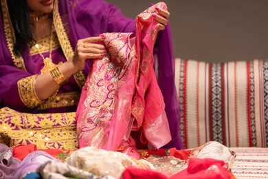 احتفالات ومناسبات سعيدة، التقاليد في التقدم لطلب يد الفتاة، عرض فستان بلون صيفي مناسب لحفلات الزفاف، صورة مقربة لشابة عربية خليجية اماراتية ترتدي الزي الشعبي التقليدي تقوم باستعراض التحضيرات والتجهيزات للزفاف بإيماءات السعادة والفرح، الاحتفال بليلة العمر