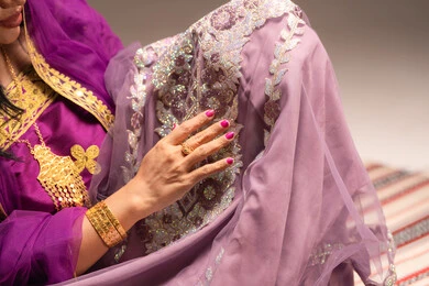 اظهار تفاصيل ازياء المناسبات السعيدة ،التزين بالحلي و المجوهرات الذهبية ،الاحتفال بليلة العمر ، العادات و التقاليد الخليجية في الزواج ، صورة مقربة لعروس عربية خليجية اماراتية ترتدي الزي الشعبي التقليدي تقوم باستعراض التحضيرات والتجهيزات للزفاف