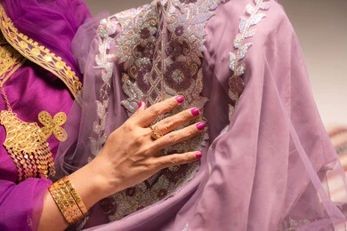 اظهار تفاصيل ازياء المناسبات السعيدة ،التزين بالحلي و المجوهرات الذهبية ،الاحتفال بليلة العمر ، العادات و التقاليد الخليجية في الزواج ، صورة مقربة لعروس عربية خليجية اماراتية ترتدي الزي الشعبي التقليدي تقوم باستعراض التحضيرات والتجهيزات للزفاف