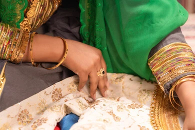 عرض تفاصيل ازياء المناسبات السعيدة ،التزين بالحلي و المجوهرات الذهبية ،الاحتفال بليلة العمر ، العادات و التقاليد الخليجية في الزواج ، صورة مقربة لعروس عربية خليجية اماراتية ترتدي الزي الشعبي التقليدي تقوم باستعراض التحضيرات والتجهيزات للزفاف