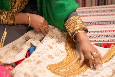 اظهار تفاصيل ازياء المناسبات السعيدة ،التزين بالحلي و المجوهرات الذهبية ،الاحتفال بليلة العمر ، العادات و التقاليد الخليجية في الزواج ، صورة مقربة لعروس عربية خليجية اماراتية ترتدي الزي الشعبي التقليدي تقوم باستعراض التحضيرات والتجهيزات للزفاف