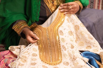 اظهار تفاصيل ازياء المناسبات السعيدة ،التزين بالحلي و المجوهرات الذهبية ،الاحتفال بليلة العمر ، العادات و التقاليد الخليجية في الزواج ، صورة مقربة لعروس عربية خليجية اماراتية ترتدي الزي الشعبي التقليدي تقوم باستعراض التحضيرات والتجهيزات للزفاف