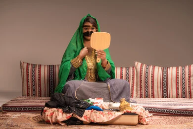 الاحتفالات والمناسبات السعيدة ، مفهوم التزيين والإطلالة المتألقة،التزين بالحلي و المجوهرات الذهبية ، استخدام مساحيق التجميل لإبراز الجمال، عروس عربية خليجية اماراتية ترتدي الزي التقليدي الشعبي تنظر لنفسها بالمرآة، الاستعداد للاحتفال بليلة العمر