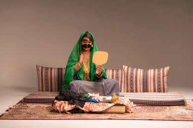 مفهوم التزيين والإطلالة المتألقة، الاحتفالات والمناسبات السعيدة ، التزين بالحلي و المجوهرات الذهبية ، استخدام مساحيق التجميل لإبراز الجمال، عروس عربية خليجية اماراتية ترتدي الزي التقليدي الشعبي تنظر لنفسها بالمرآة، الاستعداد للاحتفال بليلة العمر