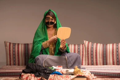 الاحتفالات والمناسبات السعيدة ، مفهوم التزيين والإطلالة المتألقة،التزين بالحلي و المجوهرات الذهبية ، استخدام مساحيق التجميل لإبراز الجمال، عروس عربية خليجية اماراتية ترتدي الزي التقليدي الشعبي تنظر لنفسها بالمرآة، الاستعداد للاحتفال بليلة العمر