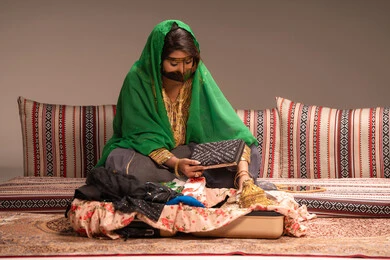 حقيبة صغيرة باللون الاسود، مفهوم التزيين والإطلالة المتألقة، التزين بالحلي و المجوهرات الذهبية ، استخدام مساحيق التجميل لإبراز الجمال، عروس عربية خليجية اماراتية ترتدي الزي التقليدي الشعبي تقوم باستعراض التحضيرات والتجهيزات للزفاف، الاستعداد للاحتفال بليلة العمر