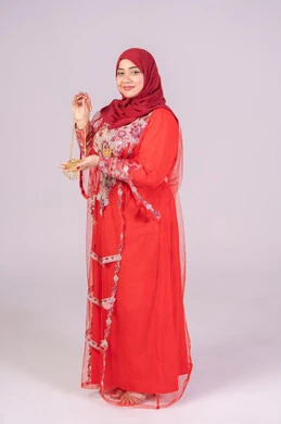 Gold jewelry and ornaments, celebrations of happy occasions and events, care for elegance and beauty, gestures of happiness and joy, a portrait of a smiling Emirati Gulf Arab woman wearing traditional attire in red displaying gold jewelry and ornaments, full-body image, white background.