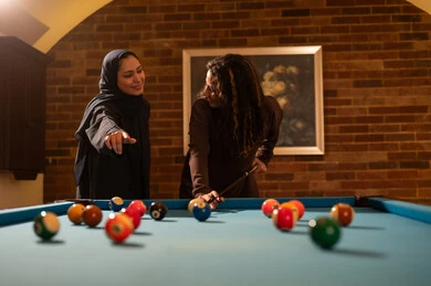 اللعب في صالات الألعاب، لاعبين محترفين, حوار ومناقشة بين الأصدقاء، مقهى البلياردو, أنشطه وهوايات شبابيه, طاولة بلياردو (السنوكر), مجموعه من السيدات العرب السعوديون الخليجيون يرتدون العباءة واحدهم ترتدي الحجاب, يلعبون لعبة البلياردو، صاله رياضيه شبابيه