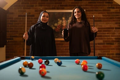 عرض شاشة سوداء على هاتف، لاعبين محترفين, حوار ومناقشة بين الأصدقاء، مقهى البلياردو, أنشطه وهوايات شبابيه, طاولة بلياردو (السنوكر), مجموعه من السيدات العرب السعوديون الخليجيون يرتدون العباءة واحدهم ترتدي الحجاب, يلعبون لعبة البلياردو، صاله رياضيه شبابيه