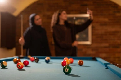 صورة سيلفي خلال اللعب، لاعبين محترفين, حوار ومناقشة بين الأصدقاء، مقهى البلياردو, أنشطه وهوايات شبابيه, طاولة بلياردو (السنوكر), مجموعه من السيدات العرب السعوديون الخليجيون يرتدون العباءة واحدهم ترتدي الحجاب, يلعبون لعبة البلياردو، صاله رياضيه شبابيه