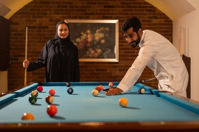 الاوقات المفضلة بين الازواج، أنشطه وهوايات شبابيه,  لاعبين محترفين, حوار ومناقشة بين الأصدقاء، مقهى البلياردو, طاولة بلياردو (السنوكر), رجل وزوجته عرب سعوديون خليجيون يرتدي يرتدي الزي التقليدي, يلعبون لعبة البلياردو، صاله رياضيه شبابيه