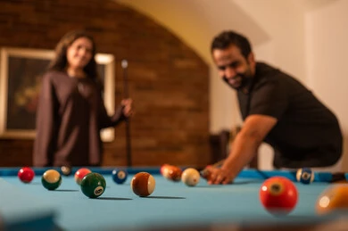 صاله رياضيه شبابيه، الابتسامة واللعب بين الشريكين , العلاقات الزوجية الناجحة،  الاوقات المفضلة بين الازواج،  حوار ومناقشة بين الأصدقاء، مقهى البلياردو, طاولة بلياردو (السنوكر), رجل وزوجته عرب سعوديون خليجيون يرتدي يرتدي الزي الكاجوال يلعبون لعبة البلياردو