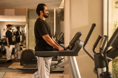 الاهتمام بالصحة واللياقة الجسدية، أهمية الرياضة لبناء جسد قوي، نشاط شبابي يساعد على المرونة البدنية, رجل سعودي يمارس تمرين لتحسين وضعية الجسم والتوازن، شاب عربي خليجي سعودي يرتدي الزي الرياضي يقوم بممارسة التمارين على جهاز المشي، استخدام الأجهزة الرياضية