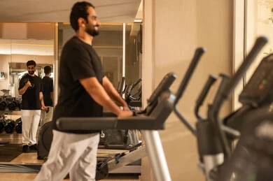 نشاط شبابي يساعد على المرونة البدنية,  أهمية الرياضة لبناء جسد قوي، الاهتمام بالصحة واللياقة الجسدية، رجل سعودي يمارس تمرين لتحسين وضعية الجسم والتوازن، شاب عربي خليجي سعودي يرتدي الزي الرياضي يقوم بممارسة التمارين على جهاز المشي، استخدام الأجهزة الرياضية