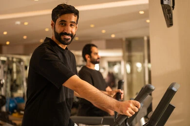 أسلوب حياة صحي،  نشاط شبابي يساعد على المرونة البدنية,  أهمية الرياضة لبناء جسد قوي، الاهتمام بالصحة واللياقة الجسدية، رجل سعودي يمارس تمرين لتحسين وضعية الجسم والتوازن، شاب عربي خليجي سعودي يرتدي الزي الرياضي يقوم بممارسة التمارين على جهاز المشي