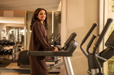 قضاء وقت ممتع أثناء التمرين على جهاز المشي،  أسلوب حياة صحية، استخدام الأجهزة التقنية الحديثة، مفهوم حرق الدهون و إنقاص الوزن، صورة لفتاة عربية خليجية سعودية ترتدي الملابس الرياضية، الاستماع للموسيقى أثناء ممارسة التمارين الرياضية على جهاز المشي